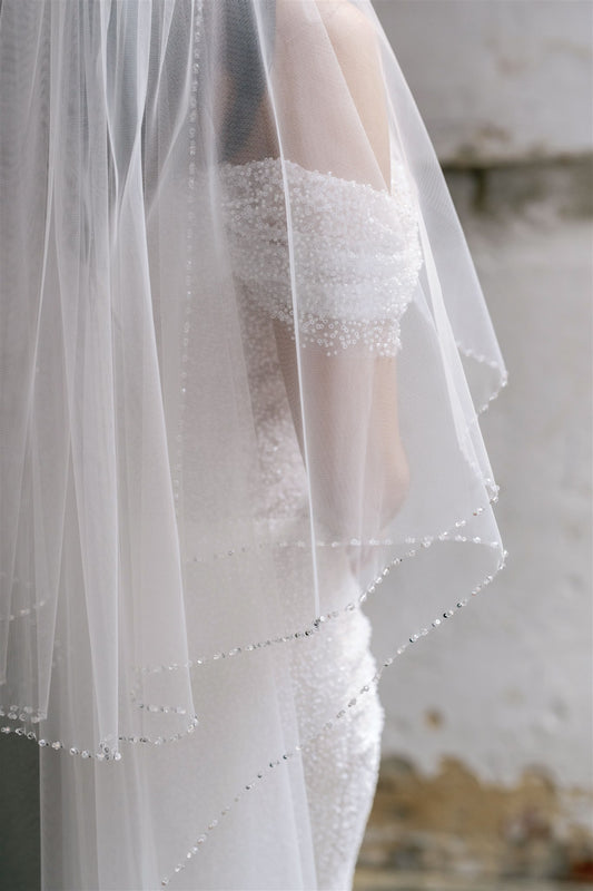 Close-up of a white wedding veil with lace details on a blurred background