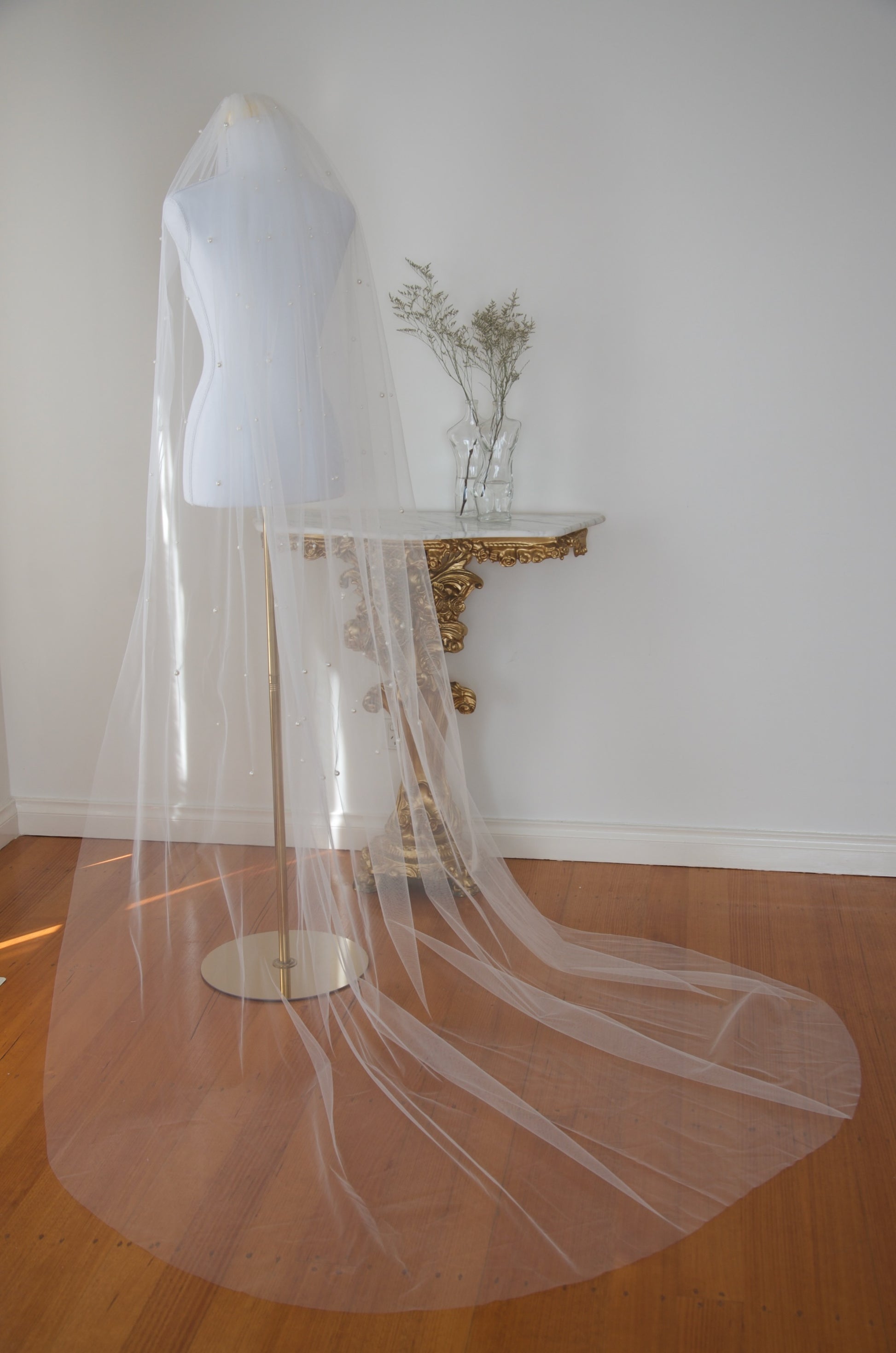White wedding veil on a mannequin with a decorative table in the background.