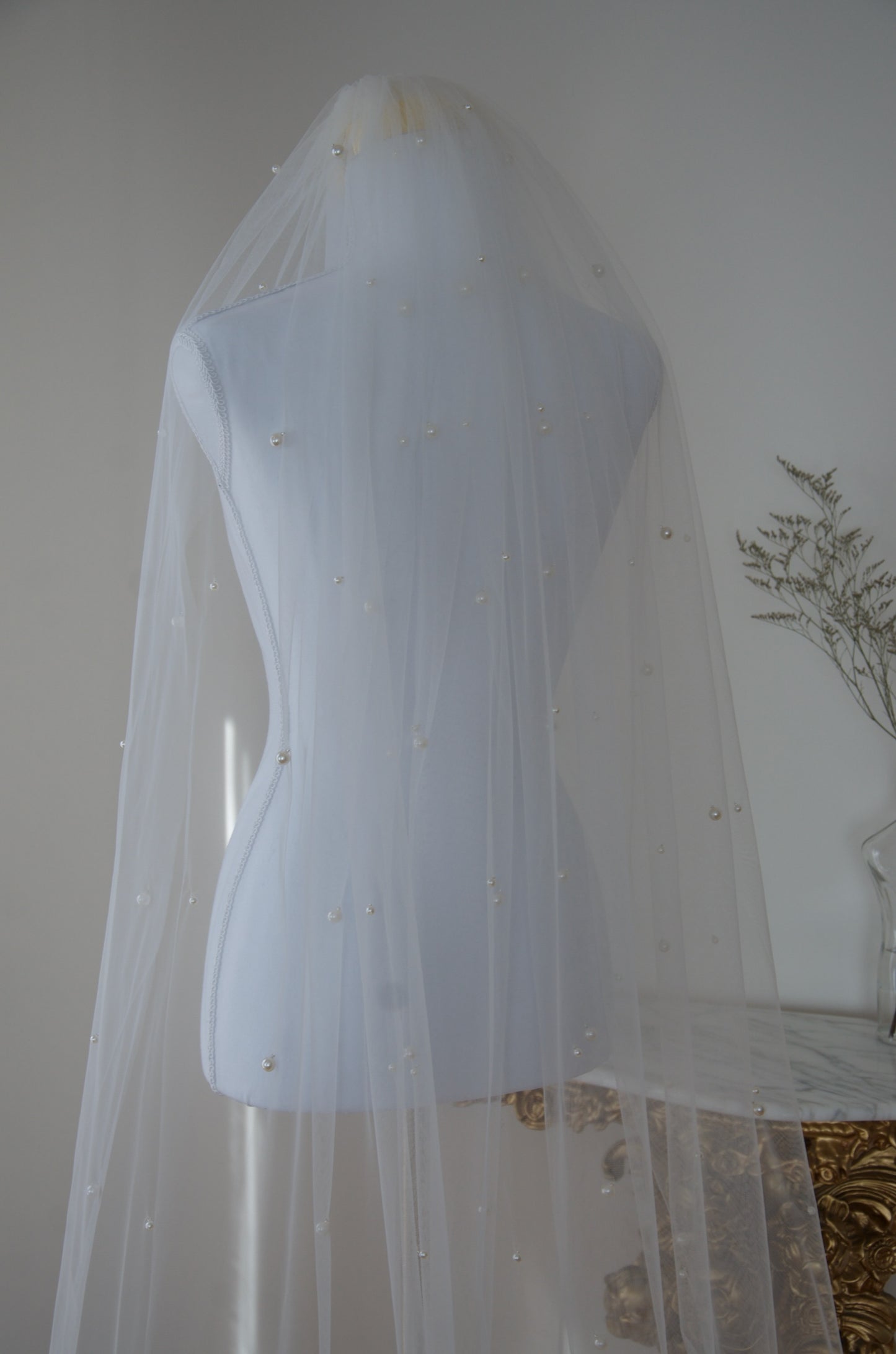 White wedding veil on a mannequin against a neutral background