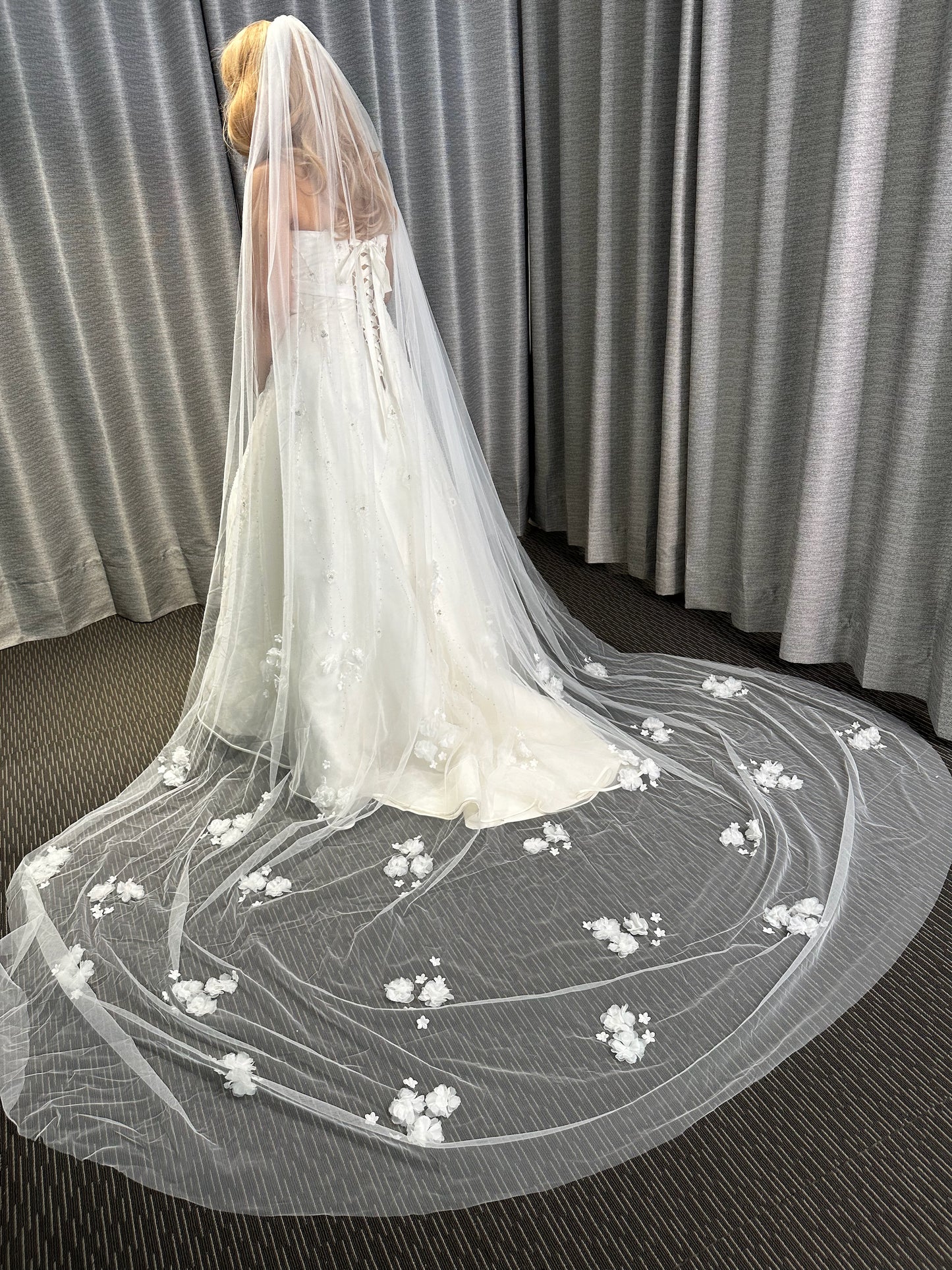 Long white wedding veil with floral embroidery on a plain background