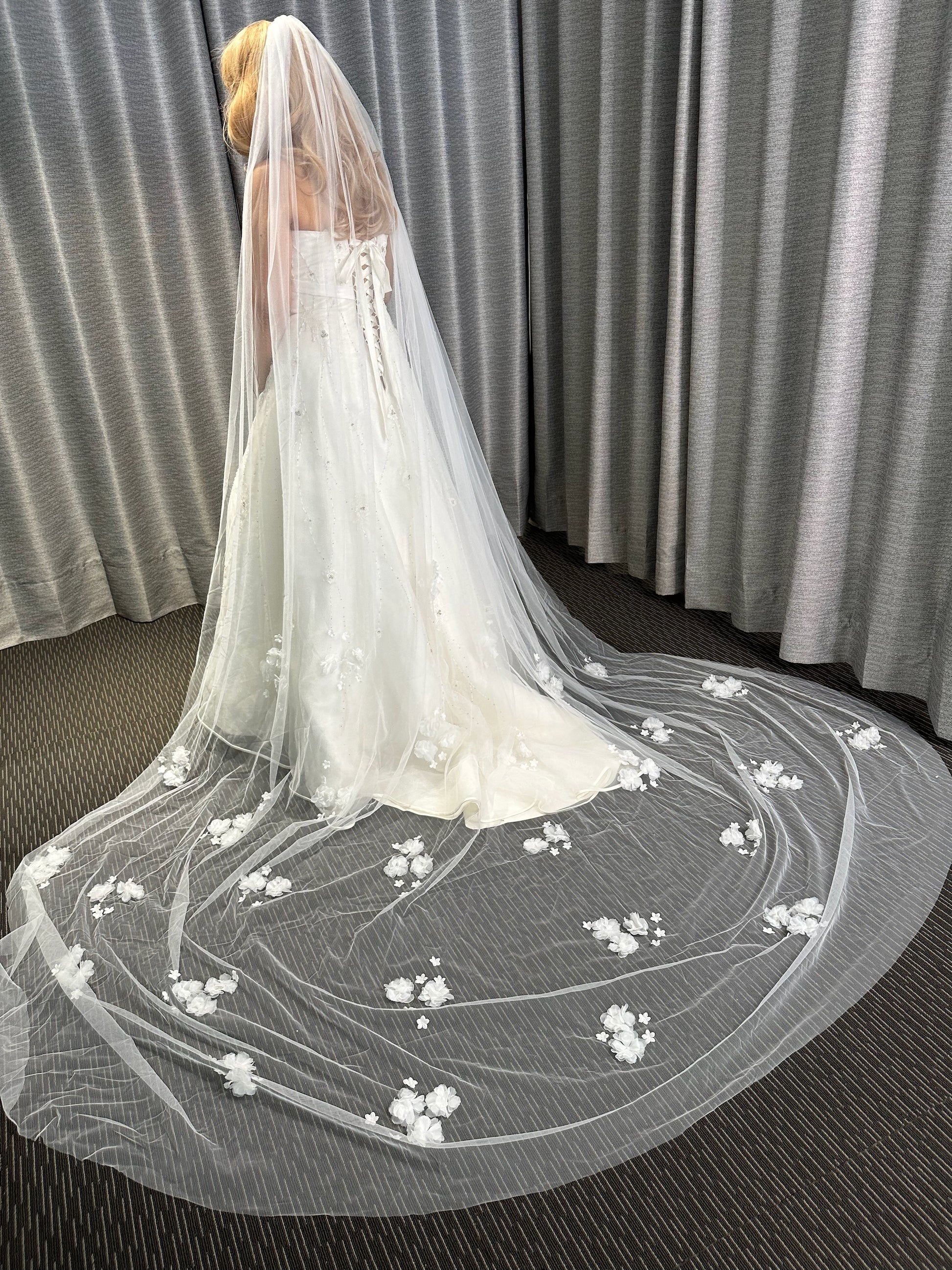 Long white wedding veil with floral embroidery on a plain background