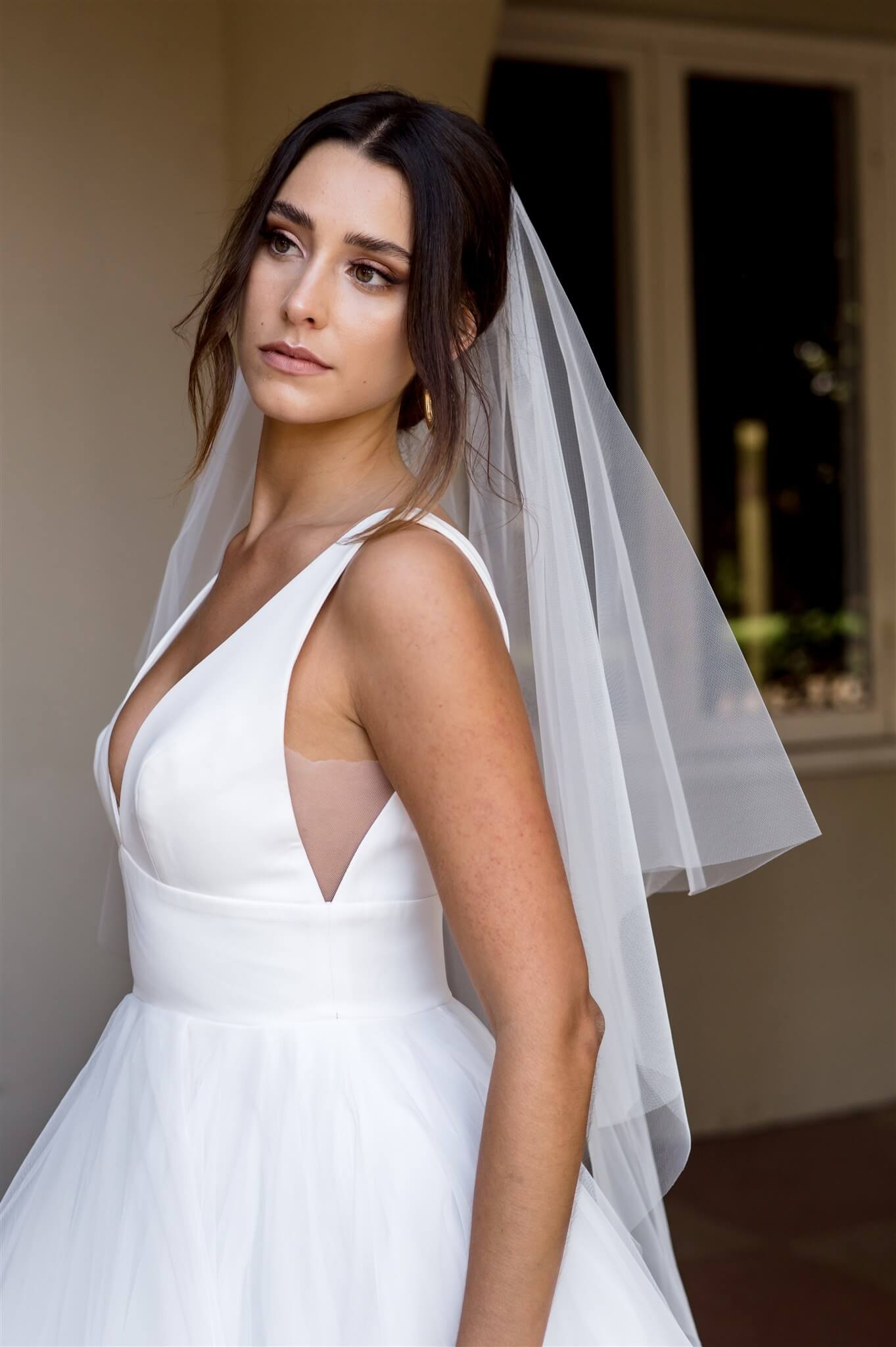 Woman wearing a white wedding dress with a veil indoors.