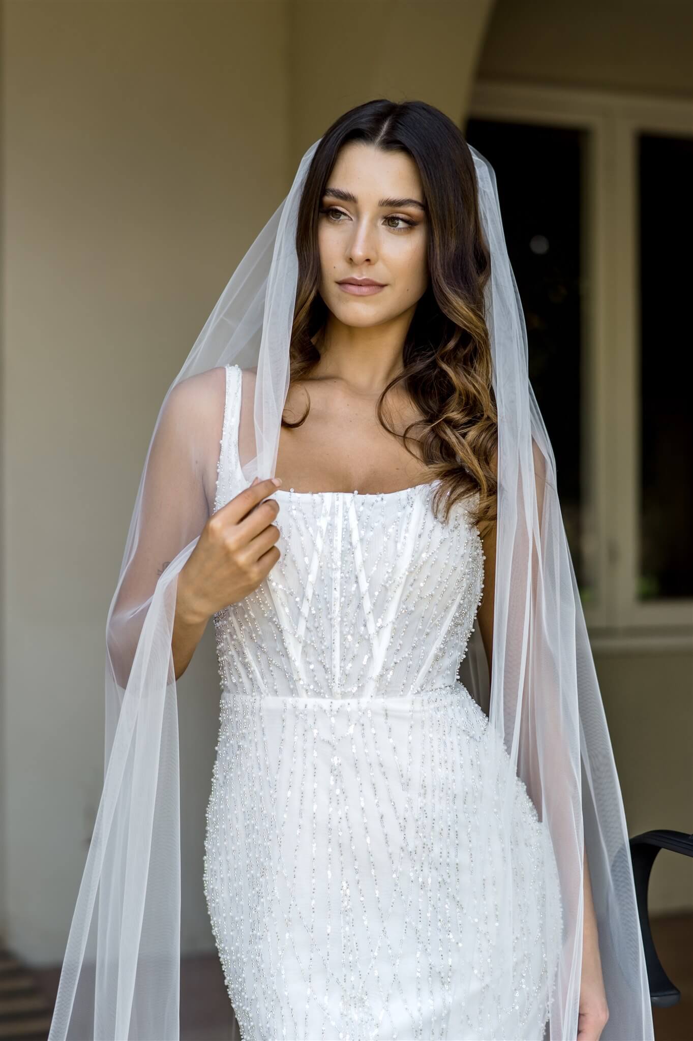 Woman wearing a white wedding dress with a veil indoors