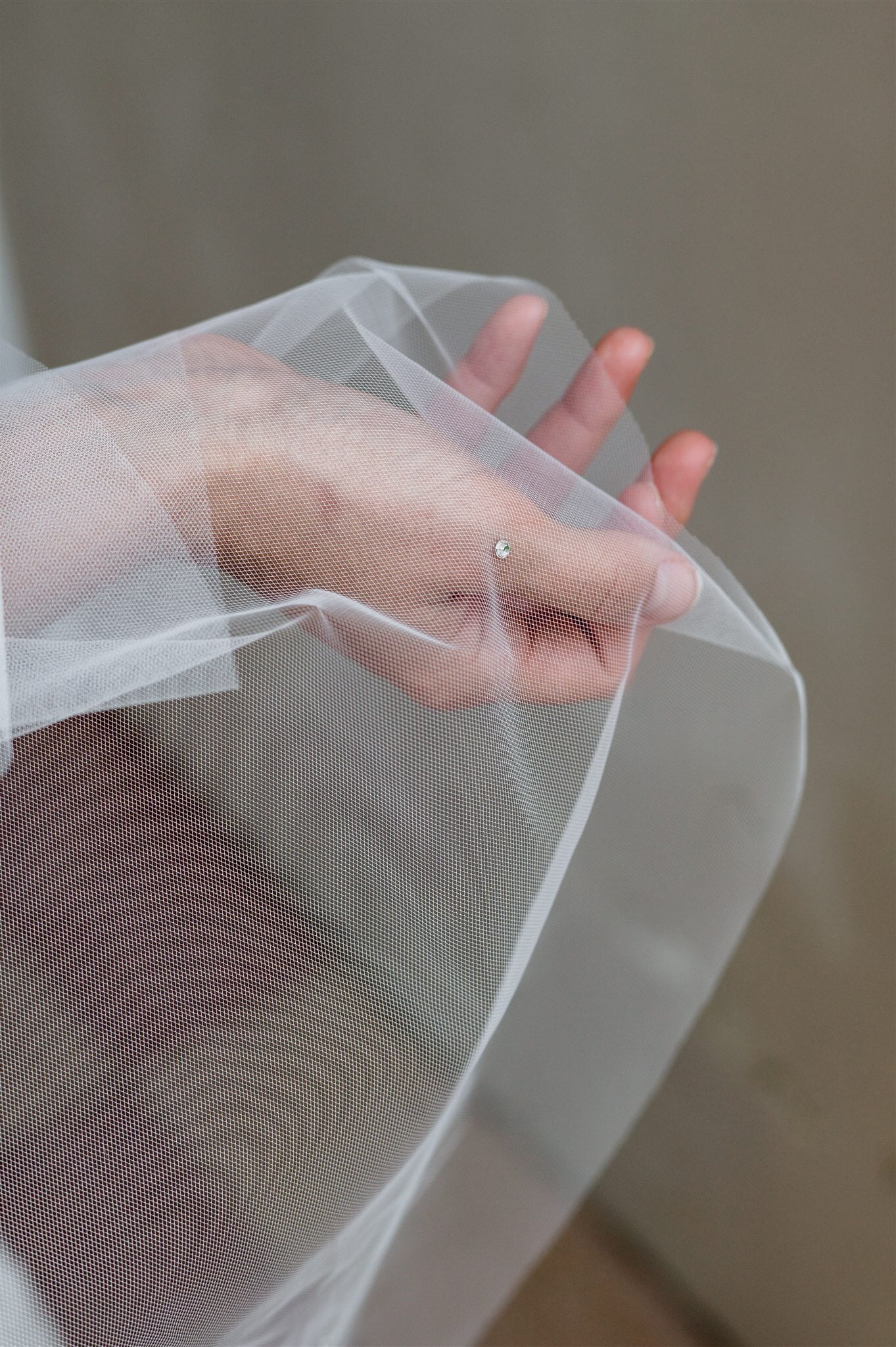 Hand holding a veil with a blurred background